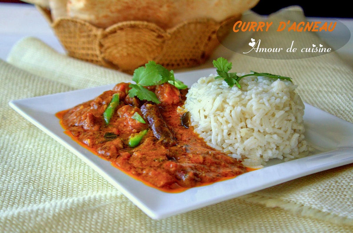 Plate of creamy lamb curry served with basmati rice, garnished with fresh coriander, on a white square plate, with a basket of Indian bread in the background.