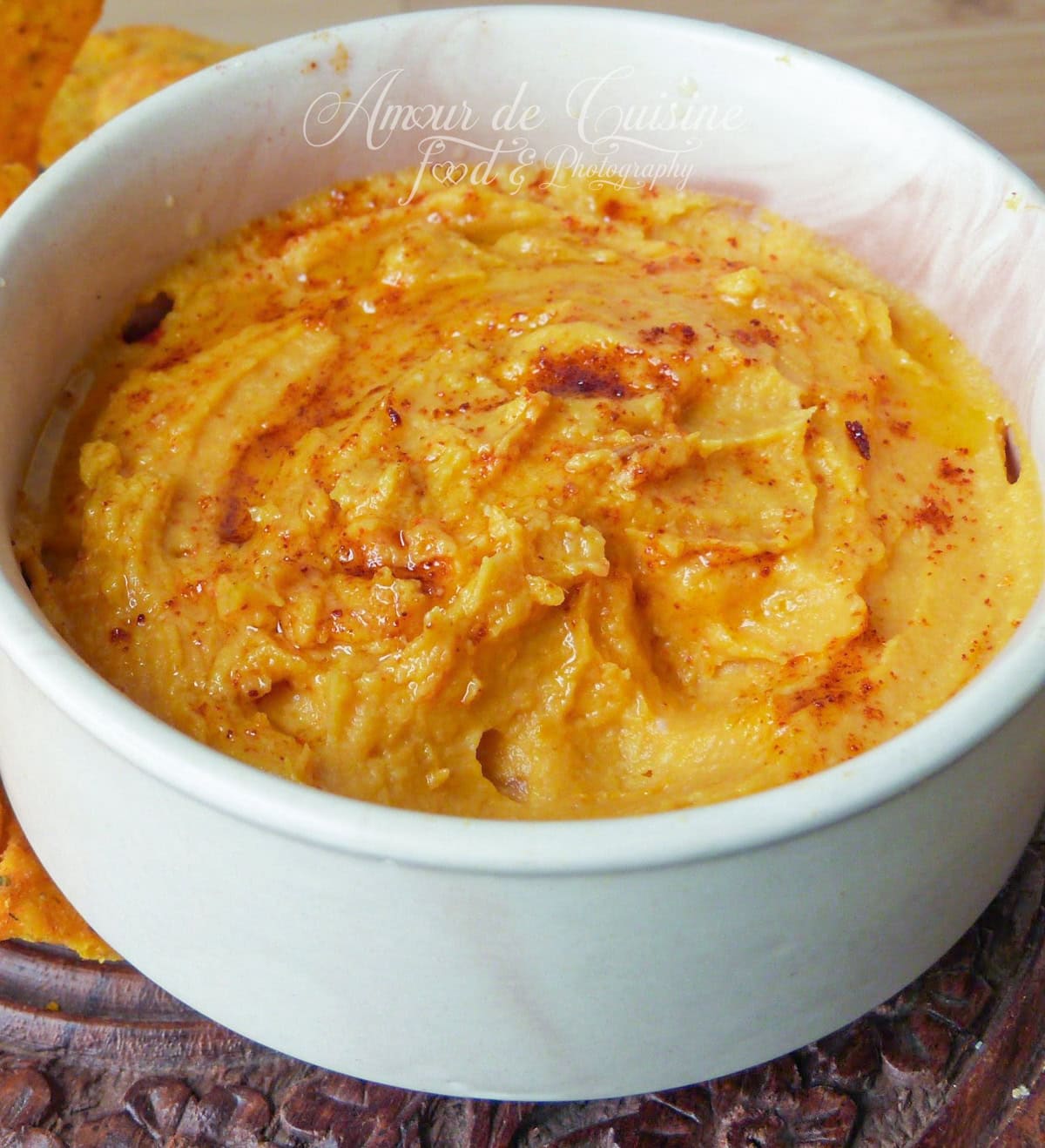 Creamy sweet potato hummus served in a white bowl, topped with a sprinkle of paprika and a drizzle of olive oil.