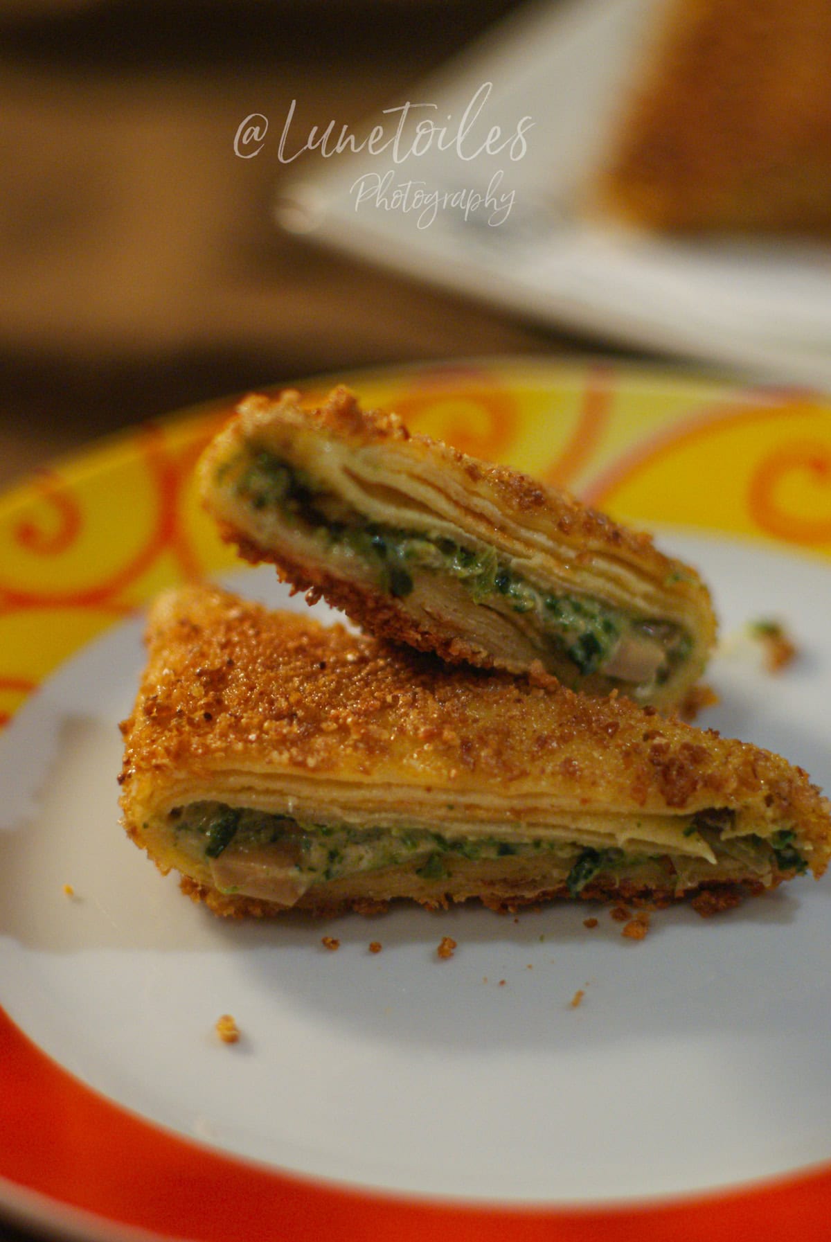 Samossas de crêpes panées coupés en deux, dorés et croustillants, montrant une farce fondante aux épinards et champignons, servis sur une assiette