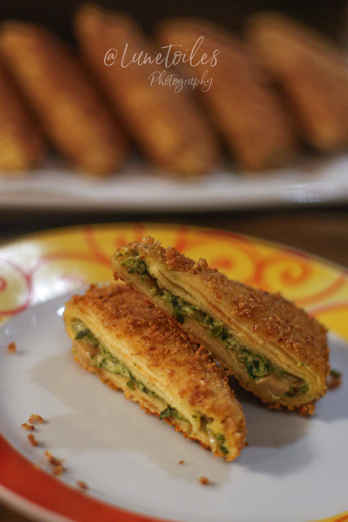 Samossas de crêpes panées coupés en deux, croustillants et dorés, avec farce aux épinards et champignons visible, servis sur une assiette au premier plan.