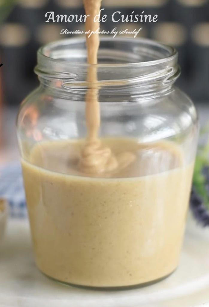 Sauce tahini maison versée dans un bocal en verre, à la texture lisse et crémeuse, prête à être conservée au frais.