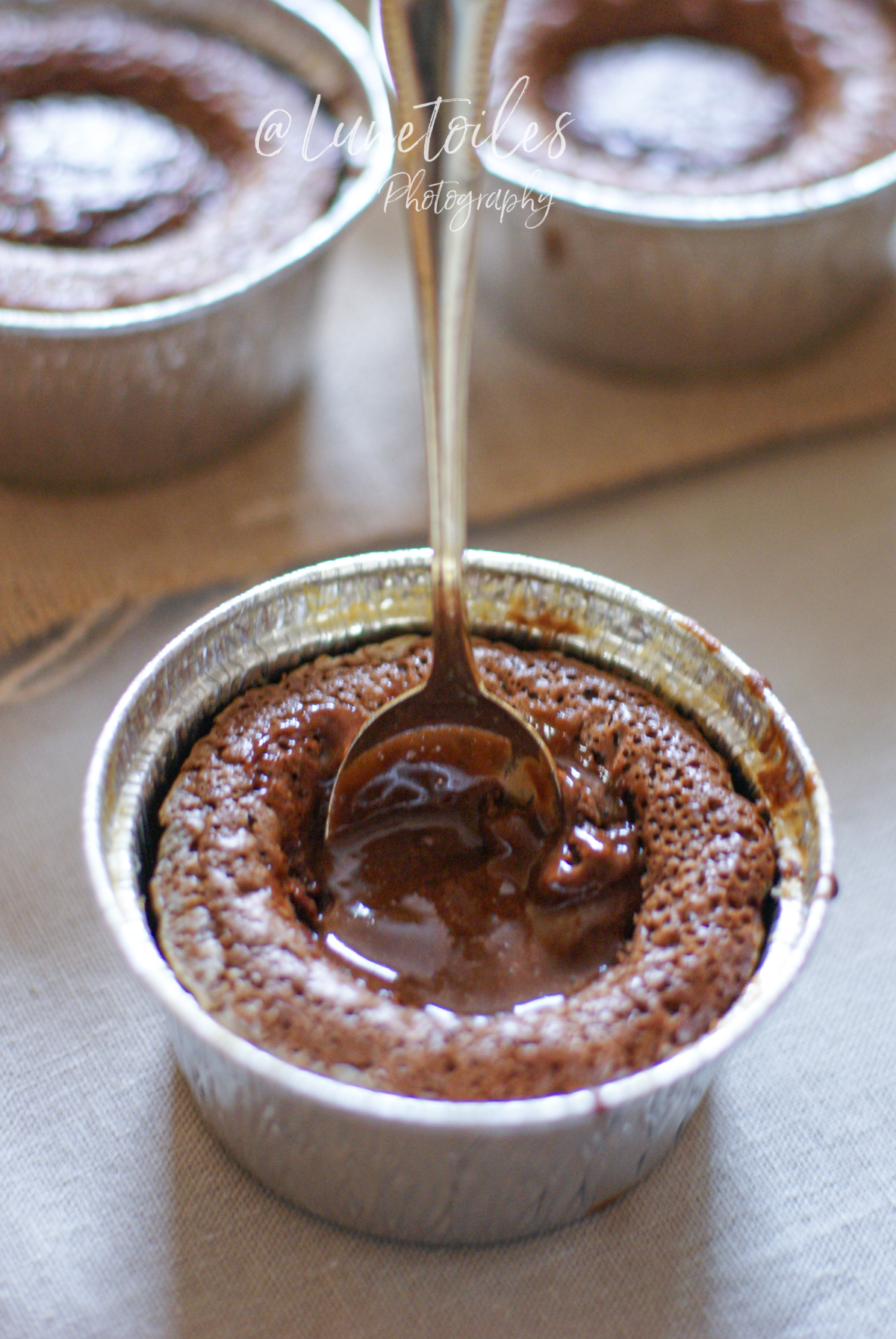 Moelleux au chocolat dans un moule en aluminium, au cœur fondant encore liquide, avec une cuillère enfoncée au centre pour révéler la texture coulante