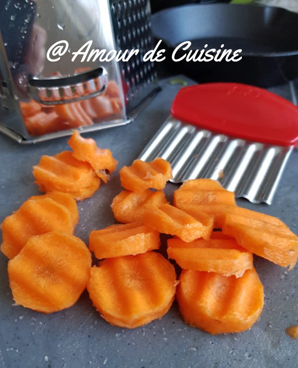 Fresh carrot slices cut with a crinkle knife, ready for the homemade Vichy carrots recipe, placed on a kitchen worktop with grater and utensils