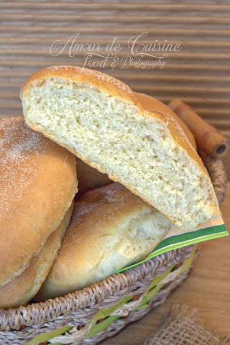 Pains maison à la semoule dans un panier, avec un pain coupé sur le dessus montrant une mie moelleuse et aérée.