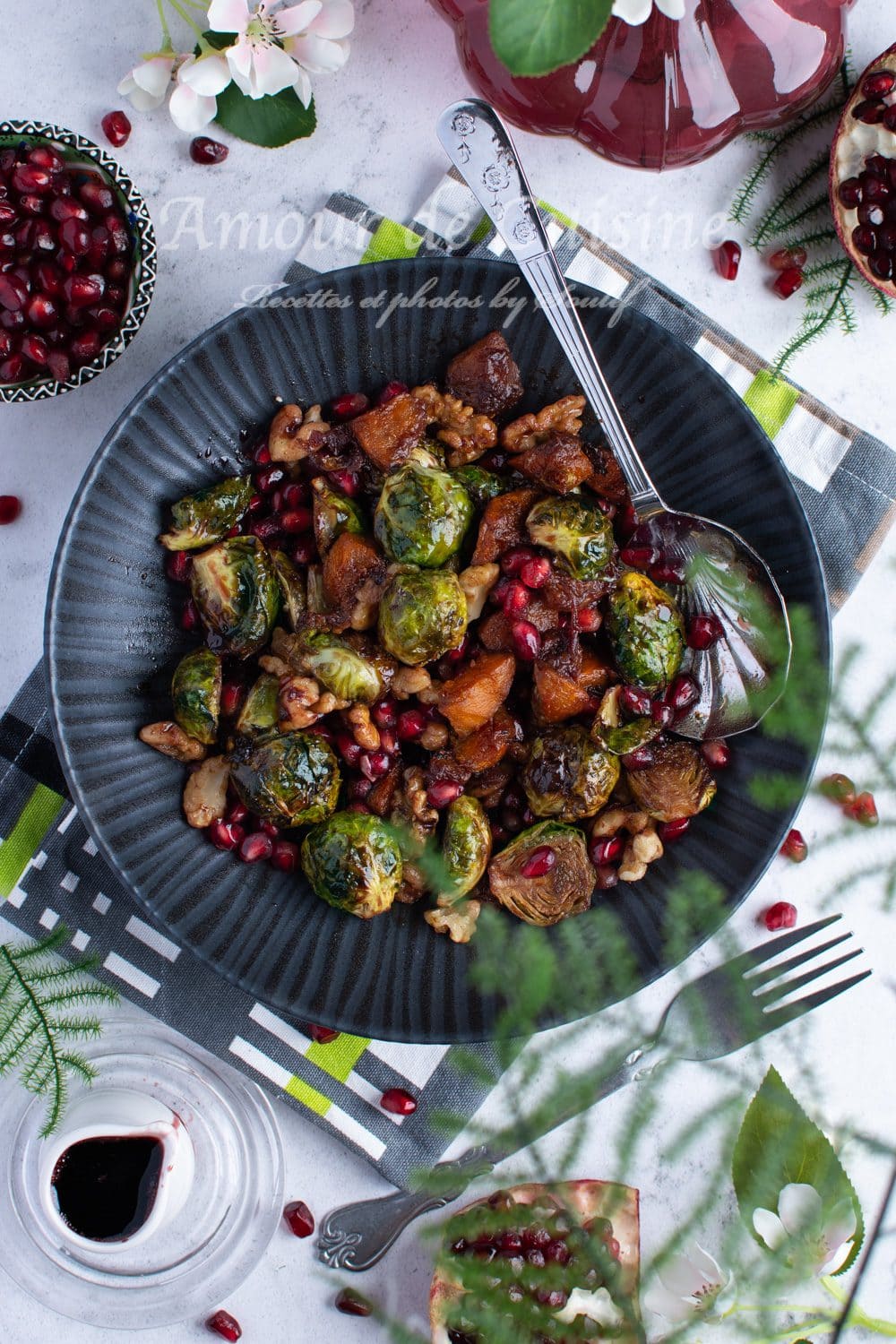 Plate of roasted Brussels sprouts and pumpkin with pomegranate molasses, topped with nuts and fresh pomegranate seeds, presented on a flower- and fruit-decorated table for a colorful, wholesome autumn meal.