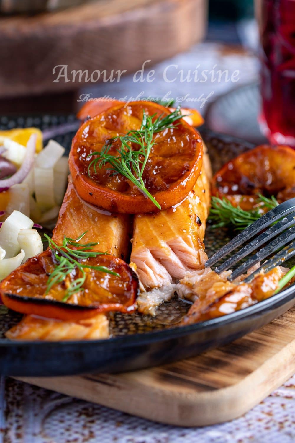 Oven-baked clementine-glazed salmon fillet, coated with a caramelized glaze and topped with citrus slices and fresh dill, served with a fennel and orange salad.