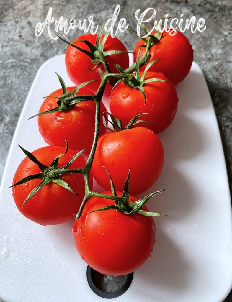 Tomates rouges fraîches sur une planche à découper, prêtes à être préparées pour une sauce aux tomates rôties maison.