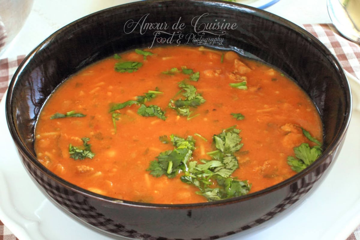 Bowl of Moroccan harira, a traditional tomato soup with lentils and chickpeas, topped with fresh coriander and served hot.