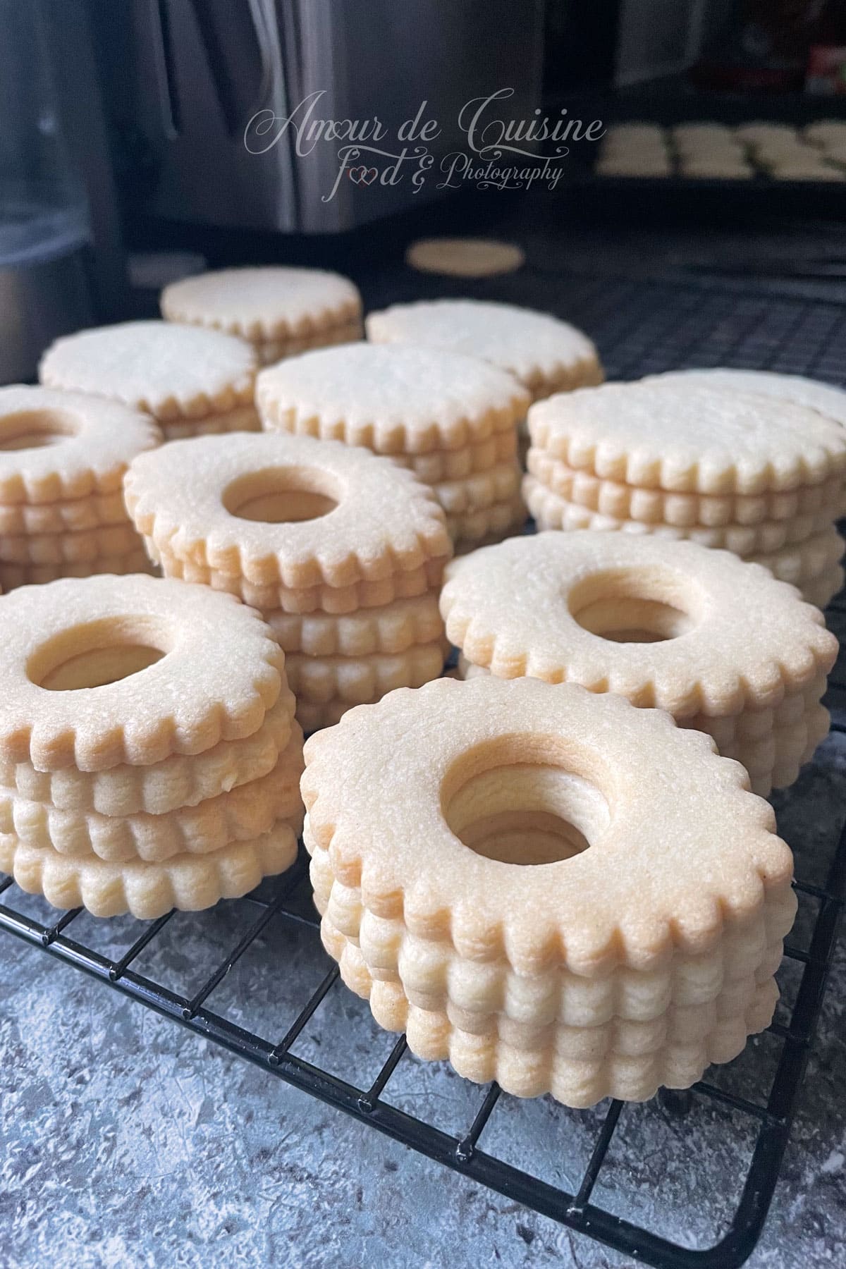 Coques de sablés maison refroidissant sur une grille, prêtes à être garnies de confiture pour préparer des biscuits fondants.
