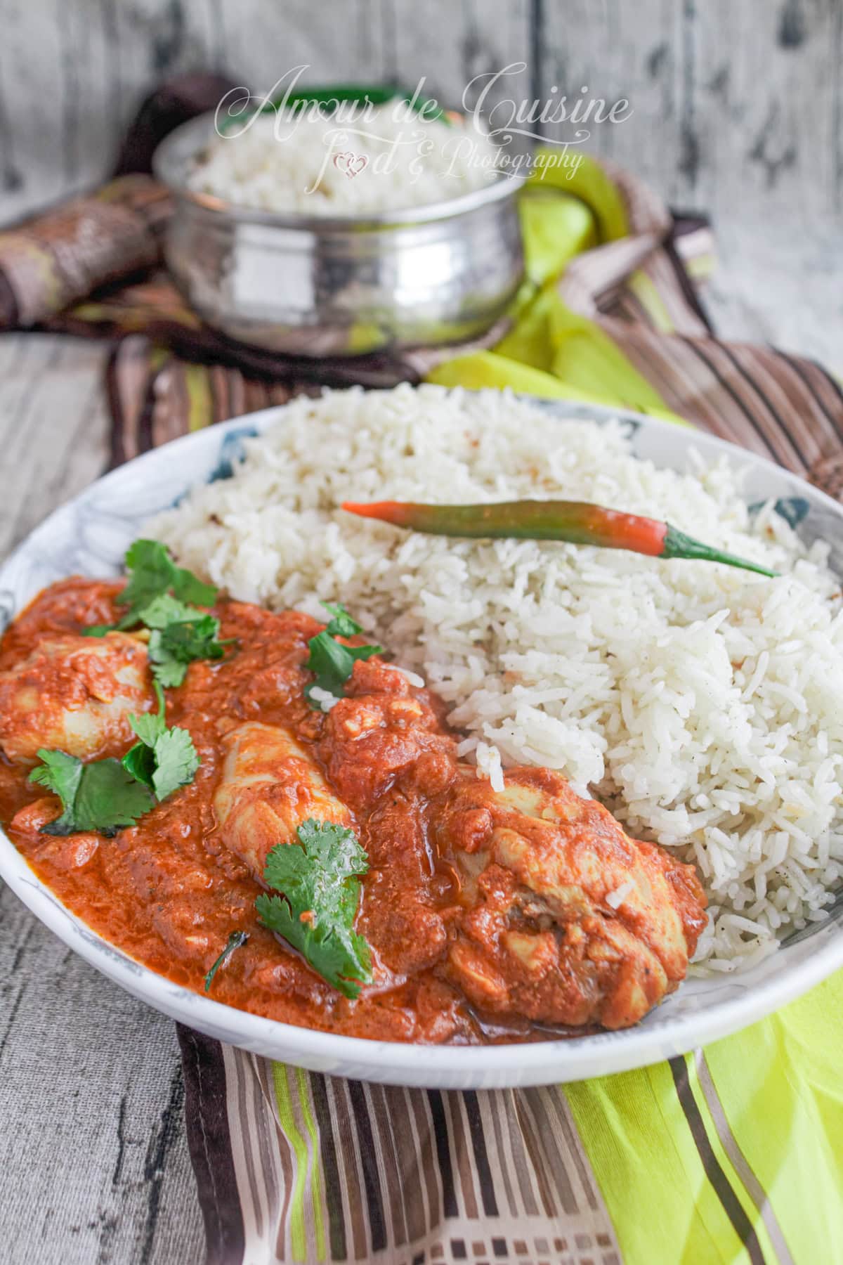 Plate of chicken tikka masala in creamy sauce served with fragrant basmati rice, garnished with fresh coriander and a red chili pepper, traditional Indian dish
