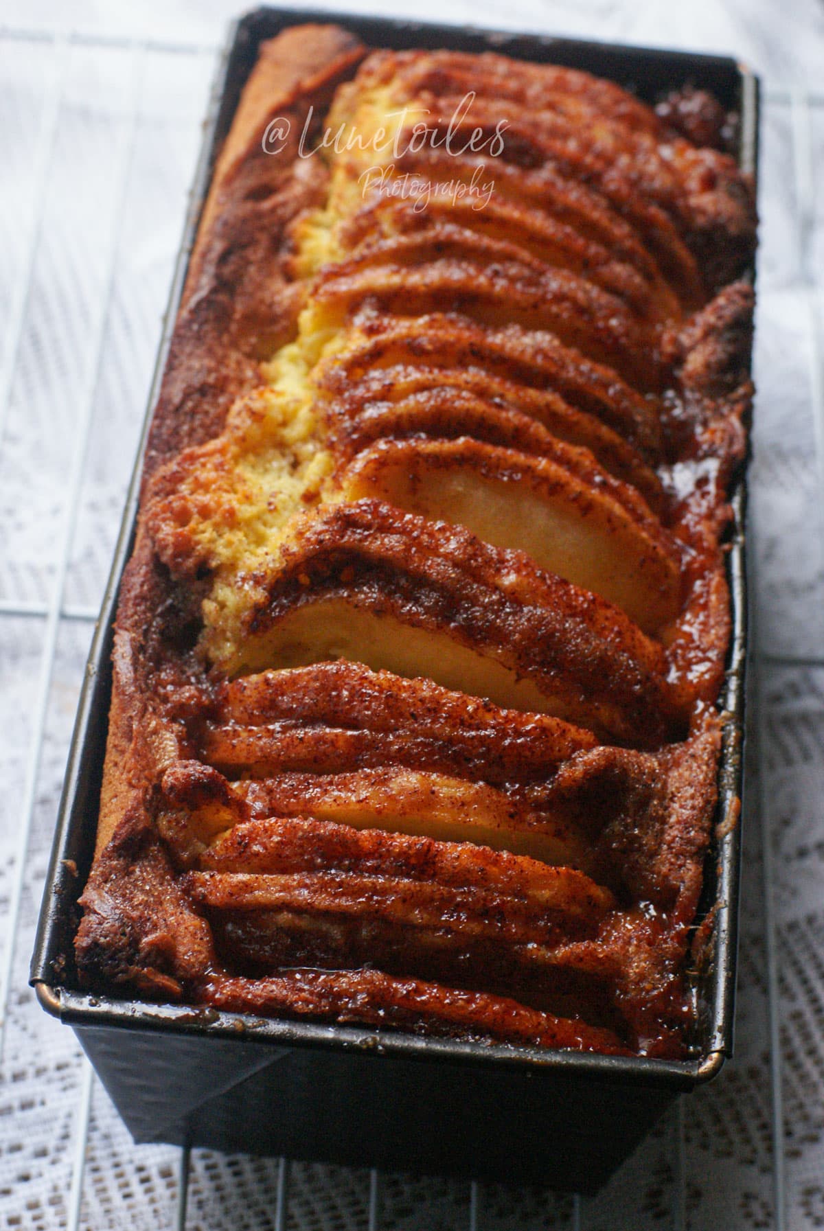 Cake aux pommes à l’ancienne dans son moule, garni de lamelles de pommes caramélisées à la cannelle et à la vergeoise.