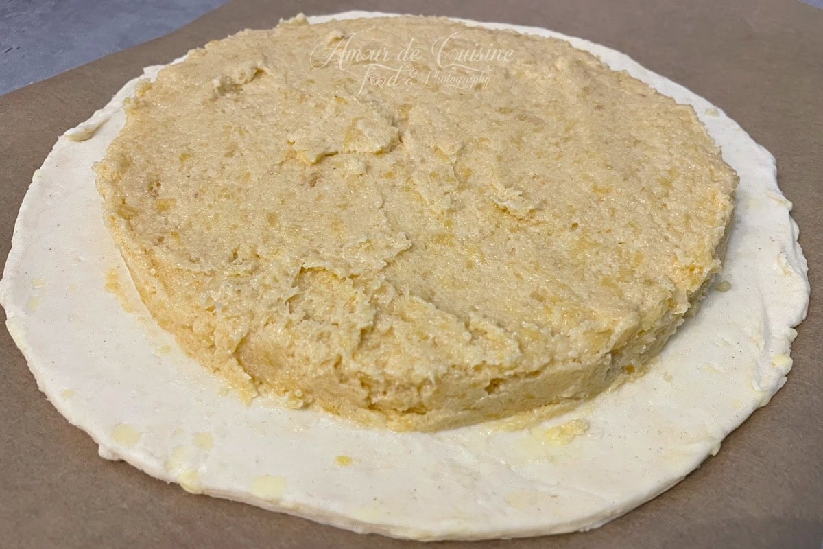 Egg-free almond filling spread into a dome on a puff pastry disc set on parchment paper, leaving a clear border all around for sealing the Galette des Rois.