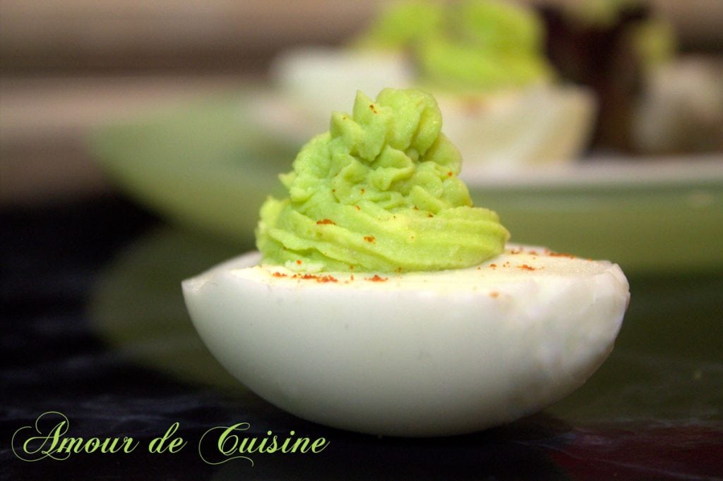 Deviled egg topped with a smooth and creamy avocado filling, beautifully piped and lightly dusted with Espelette pepper, served on a plate