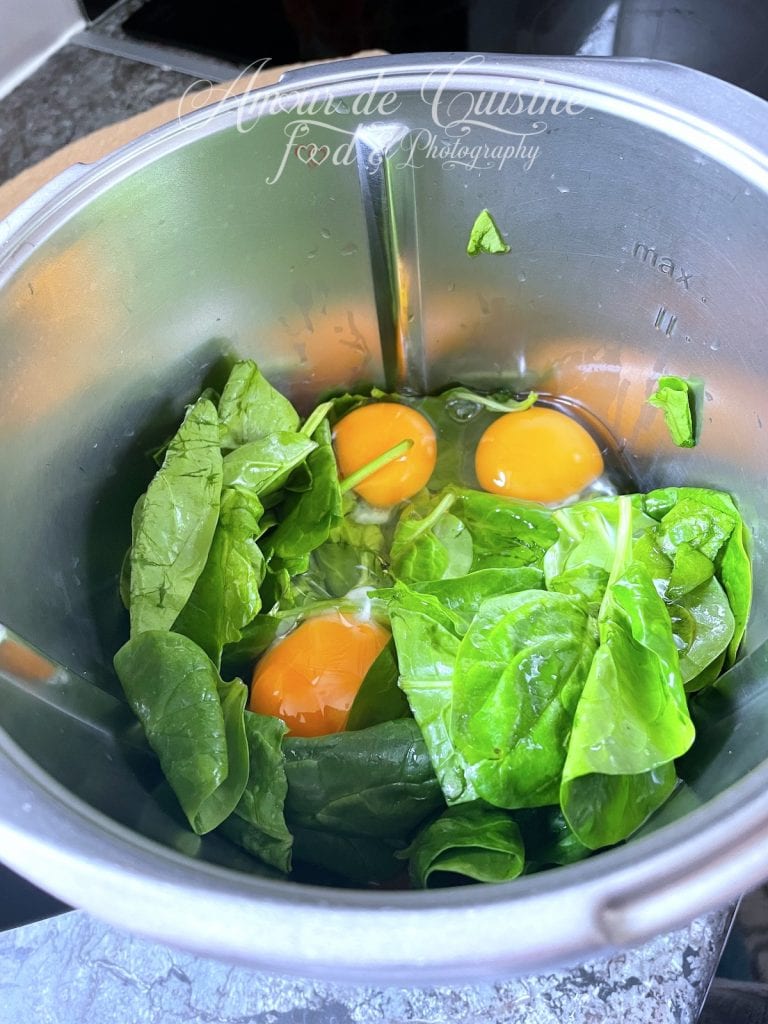 Feuilles d’épinards fraîches et œufs entiers dans le bol mixeur du thermomix, prêts à être mixés pour préparer des tortillas saines aux épinards