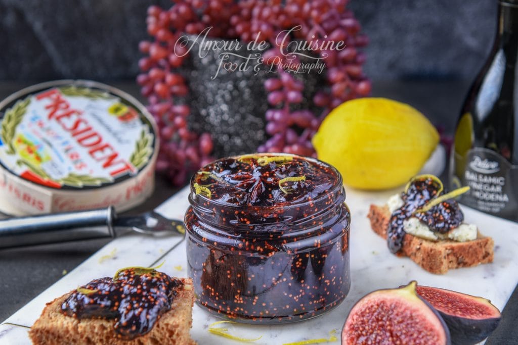 Bocal de confit de figues au vinaigre balsamique entouré de figues fraîches, pain grillé garni, fromage Président et bouteille de vinaigre balsamique