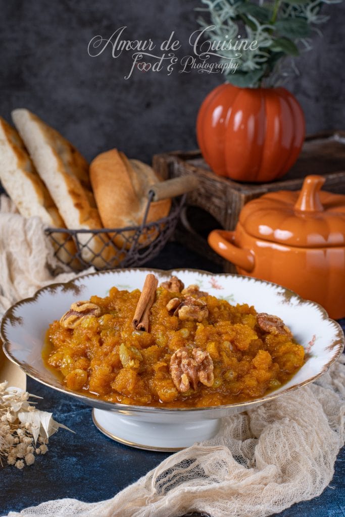 Purée de potiron sucrée “mrouzia constantinoise” servie dans une assiette élégante, décorée de noix et d’un bâton de cannelle, accompagnée de pain maison et présentée dans une ambiance automnale chaleureuse.