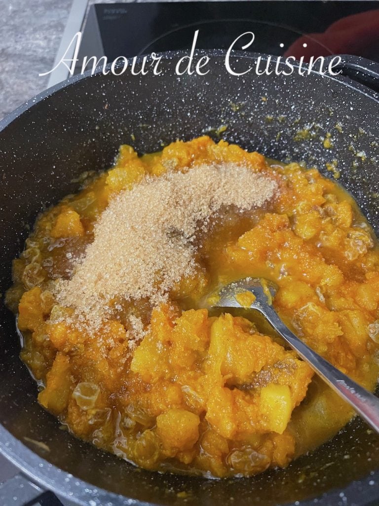 Ajout du sucre dans la cocotte de mrouzia constantinoise, avec des morceaux de potiron fondants et des raisins secs, pour obtenir une texture douce et légèrement caramélisée