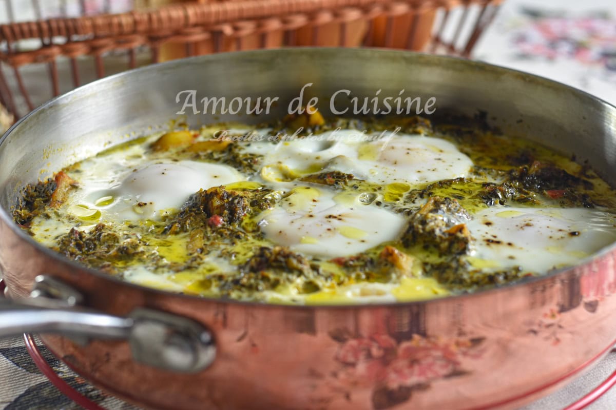A copper skillet filled with spinach and potato shakshuka, featuring poached eggs simmering in a savory, spiced green sauce with olive oil glistening on top.