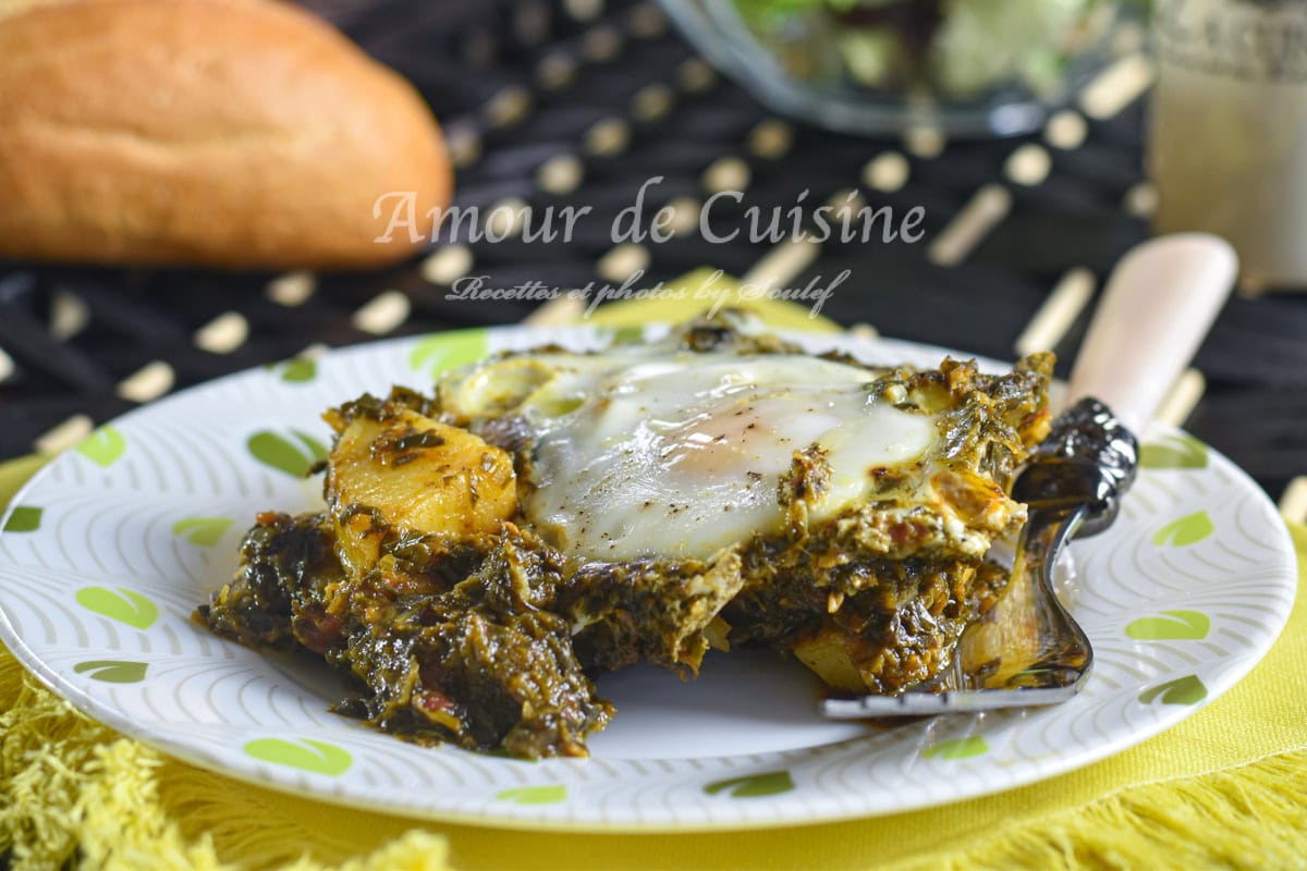 A hearty serving of spinach and potato shakshuka with a soft-baked egg on top, presented on a patterned plate with a fork, accompanied by crusty bread and a salad in the background.