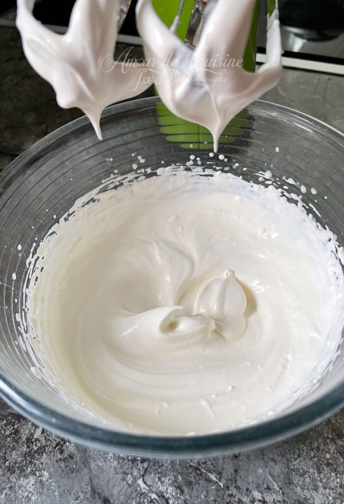 Crème chantilly montée au fouet dans un saladier, pour garnir une pavlova ou un dessert aux fruits