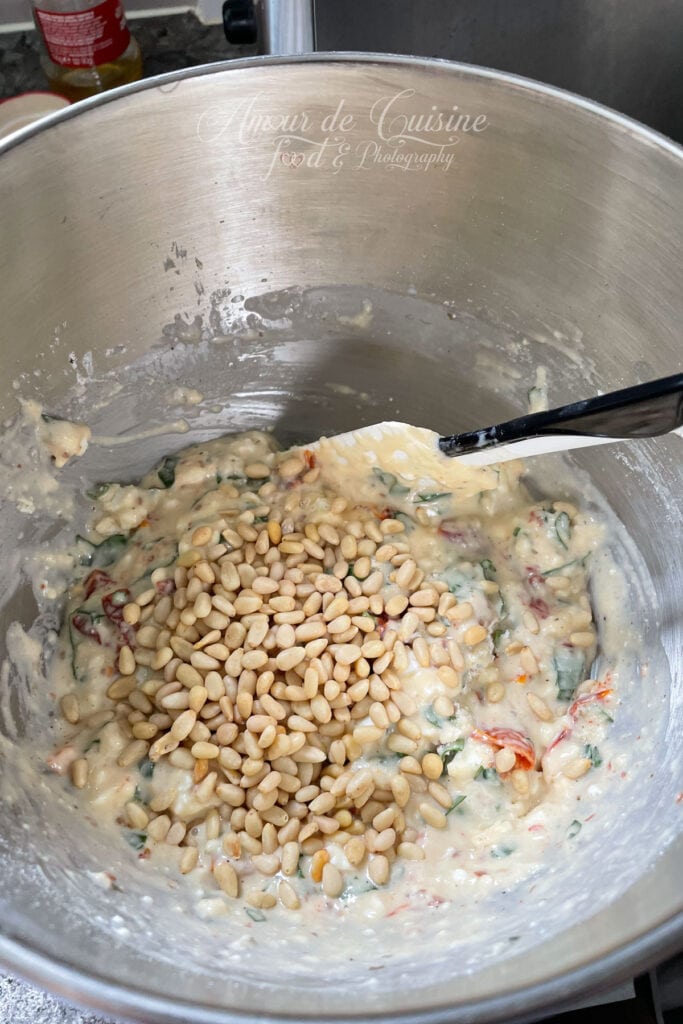 Pâte à cake salé aux tomates séchées, feta et basilic avec ajout des pignons de pin avant cuisson.